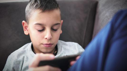 在家里使用智能手机和玩电子游戏的年轻男孩视频的预览图