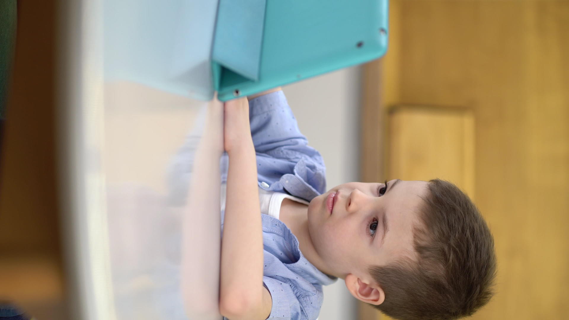 学龄前儿童坐在桌子上看一台数字平板电脑视频的预览图