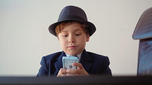 这个小男孩看起来像个企业家在办公室里数钱视频的预览图