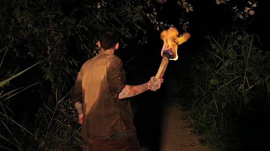 晚上男孩手里拿着火炬在树林里视频的预览图