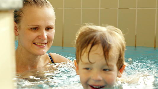 快乐的男孩和他的母亲在游泳池里游泳视频的预览图