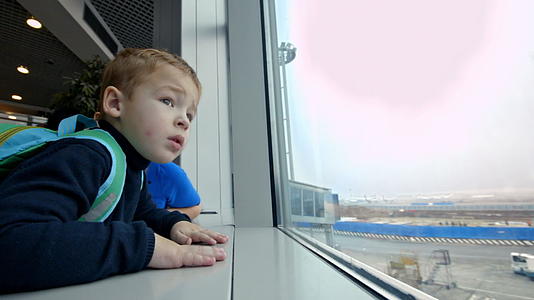 母亲和小儿子看着机场窗外的窗户视频的预览图