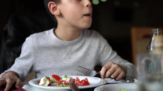 英俊的男孩吃新鲜蔬菜沙拉、番茄、辣椒、洋葱、洋葱、洋葱视频的预览图