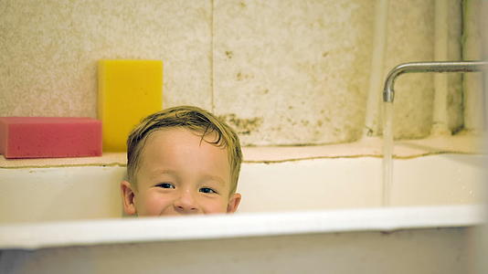 洗澡时男孩笑着坐在浴室里视频的预览图