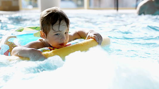 小男孩在游泳池里用橡皮环游泳视频的预览图
