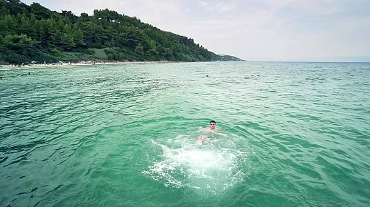 快乐的男孩在海绿水中慢慢地游泳视频的预览图