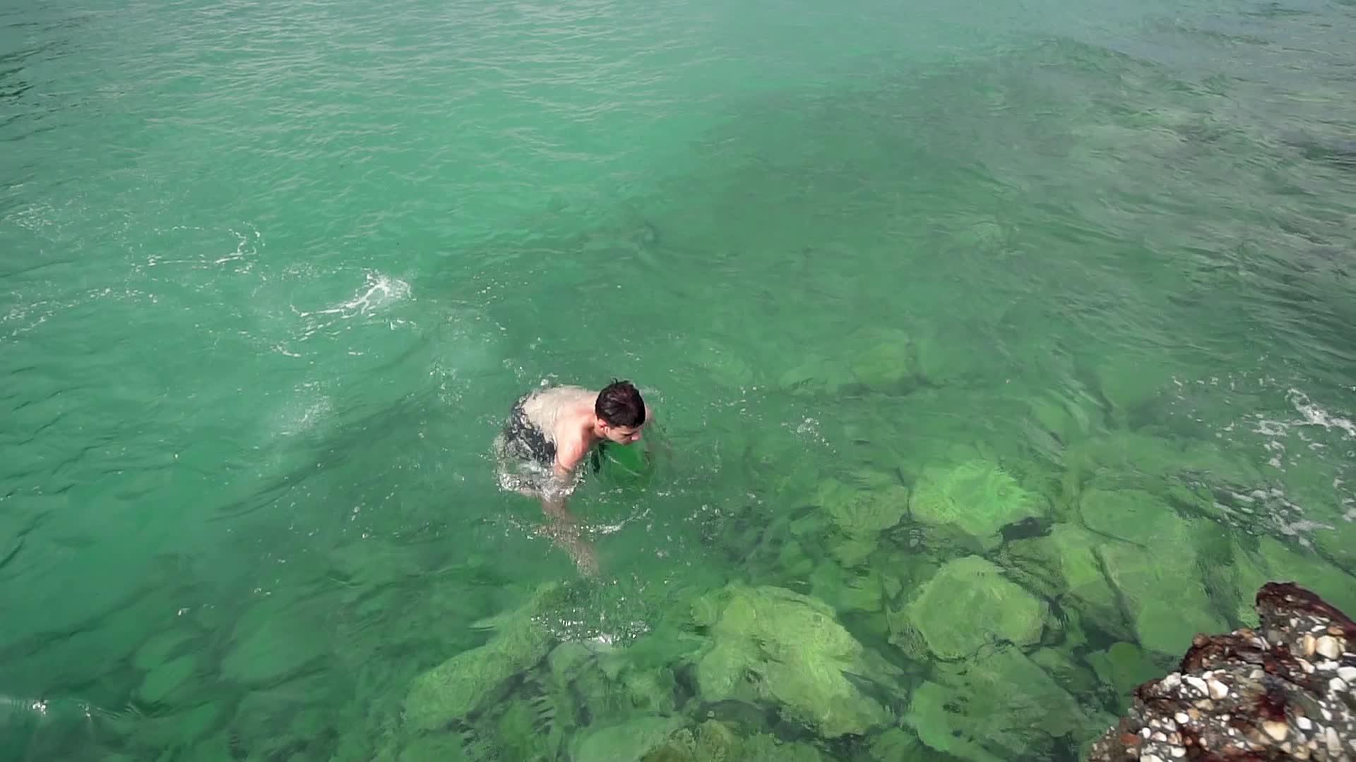 快乐的男孩在海绿松石水中慢慢地游泳视频的预览图