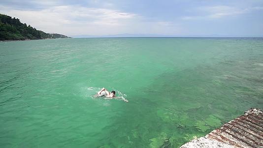 快乐的男孩在海绿松石水中慢慢地游泳视频的预览图