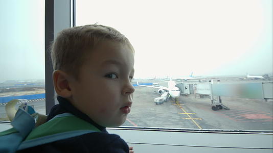 小男孩看着窗外指着飞机视频的预览图