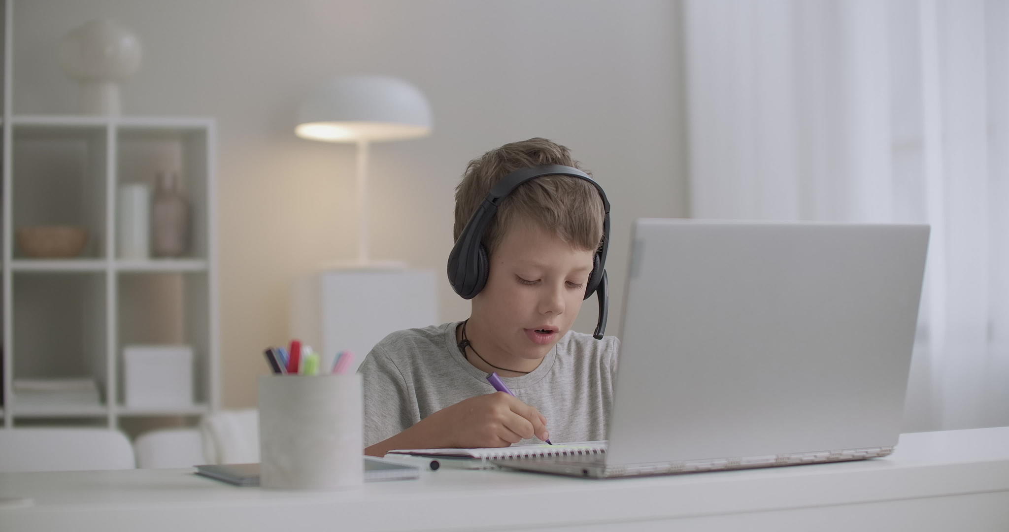 年轻男孩用耳机画画听音乐白天独自坐在家里画画视频的预览图
