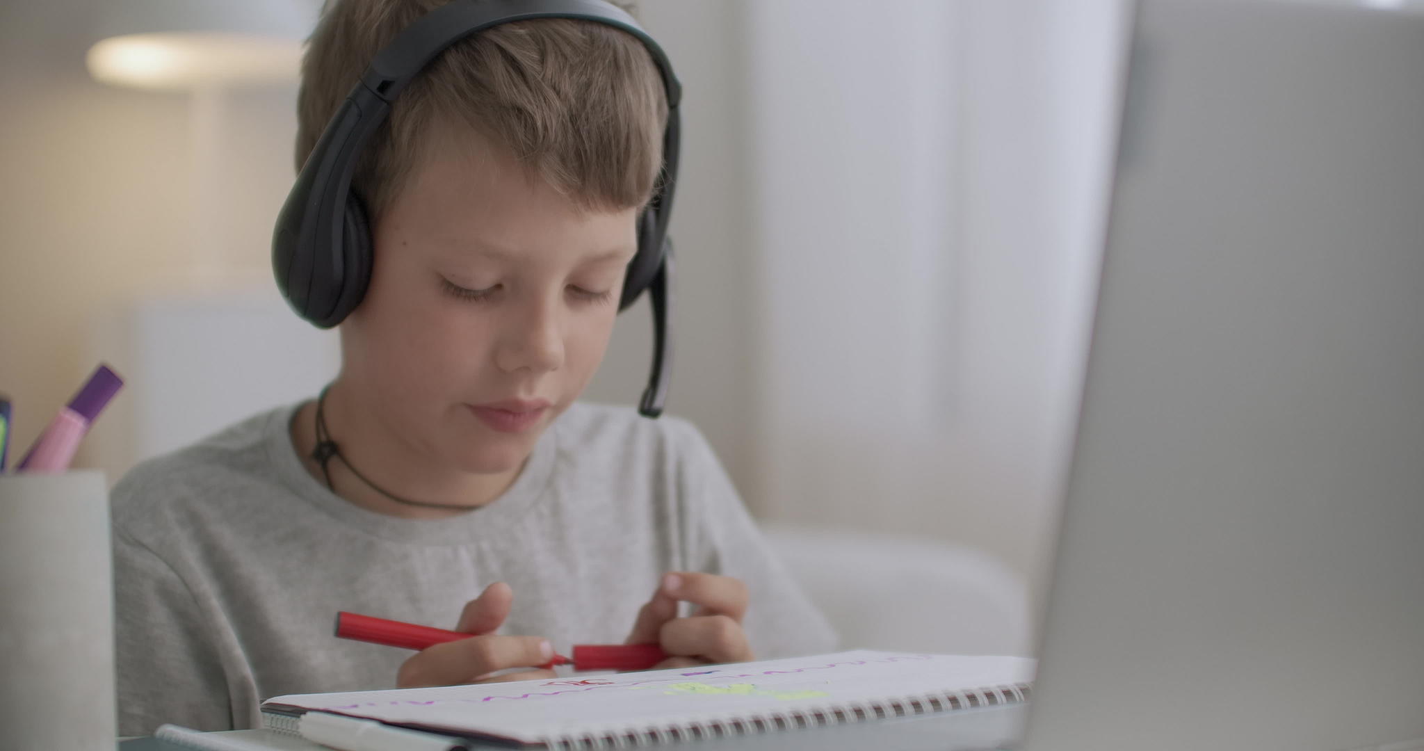 小男孩头上戴着耳机的肖像坐在他房间的桌子上视频的预览图