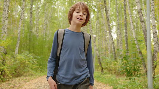 秋天公园里走着背包的年轻男孩视频的预览图