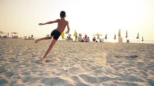超级活跃的男孩在沙滩上微笑着跳跃视频的预览图