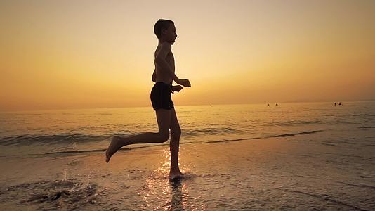 日落时在海浪中奔跑的男孩视频的预览图