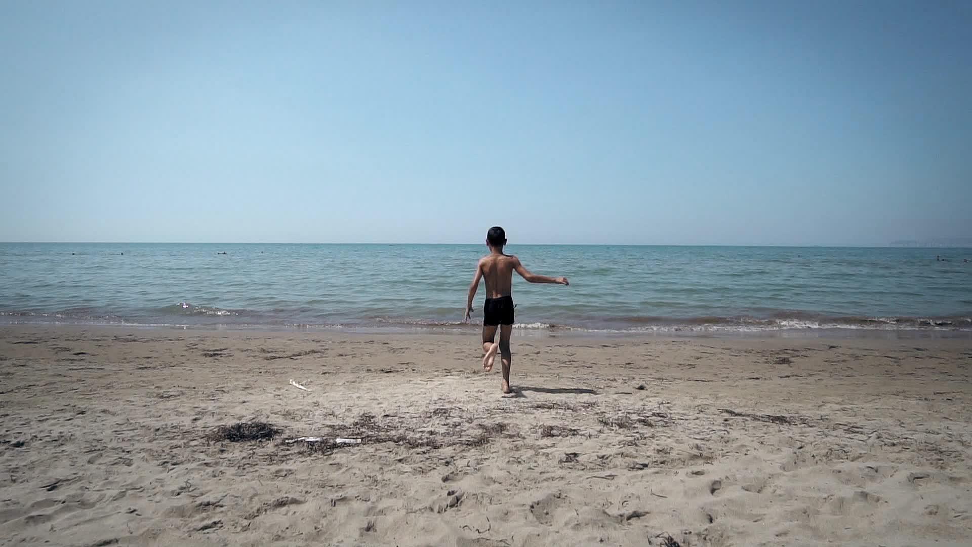 小男孩在海滩上慢跑视频的预览图