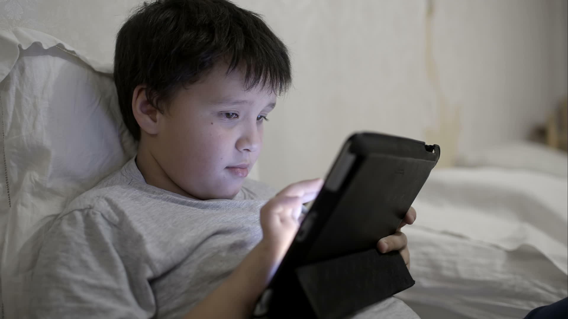 躺在床上用平板电脑的年轻男孩视频的预览图