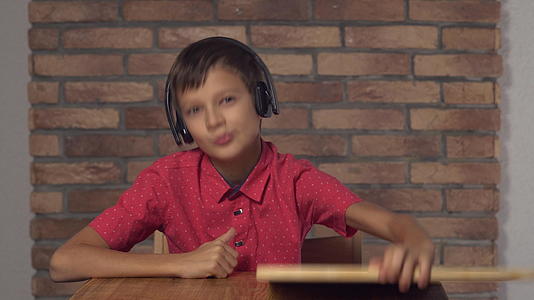 坐在桌旁的孩子拿着翻页的图片在红砖墙上放着字母音乐视频的预览图