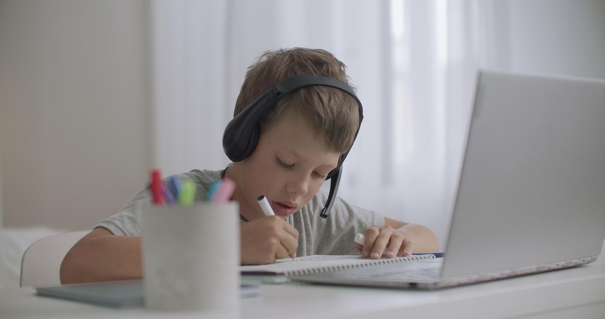 孩子们的男孩们正在用笔记本电脑和手持耳机听音乐视频的预览图