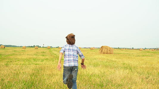 在乡村的秋天在田野里逃跑的青少年背着大草原的风景看到了青少年视频的预览图