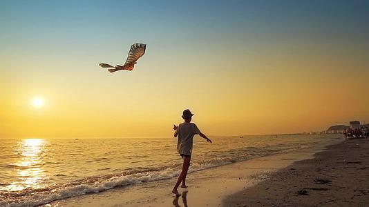 在夏天的背景中 一个年轻男孩带着风筝在空荡荡的海滩上奔跑视频的预览图