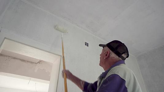 高级男子用滚筒在平地上画内墙房屋翻新或重新装修的概念视频的预览图