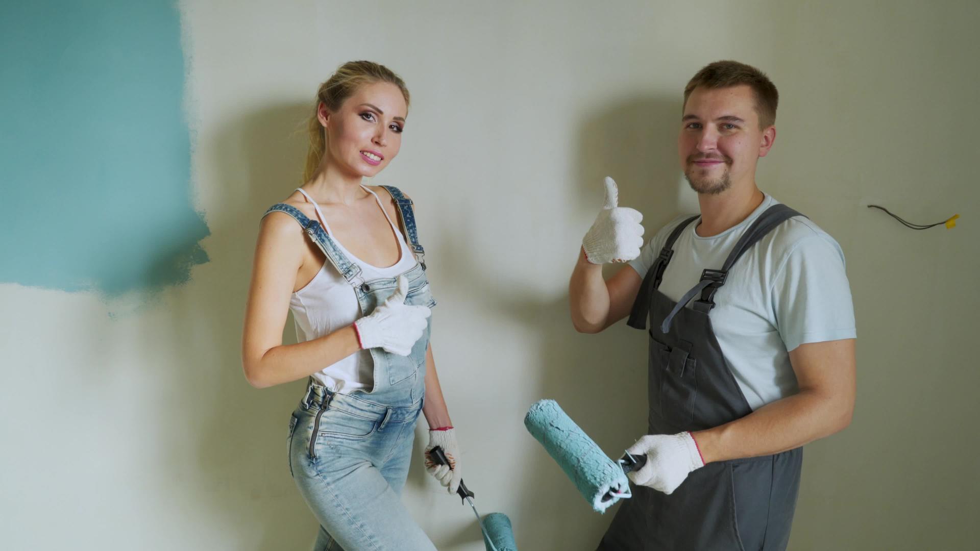 年轻夫妇的家庭工作人员在公寓里用滚动机油漆墙壁或墙壁视频的预览图