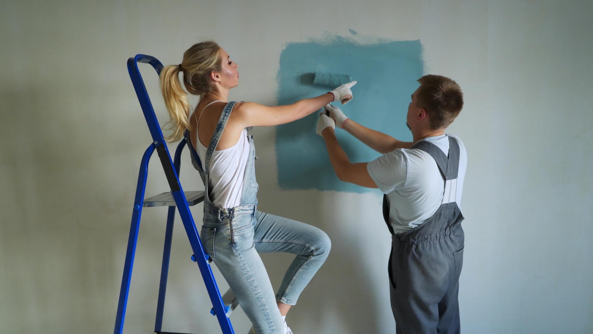 年轻夫妇的家庭工作人员在公寓里用滚动机油漆墙壁或墙壁视频的预览图