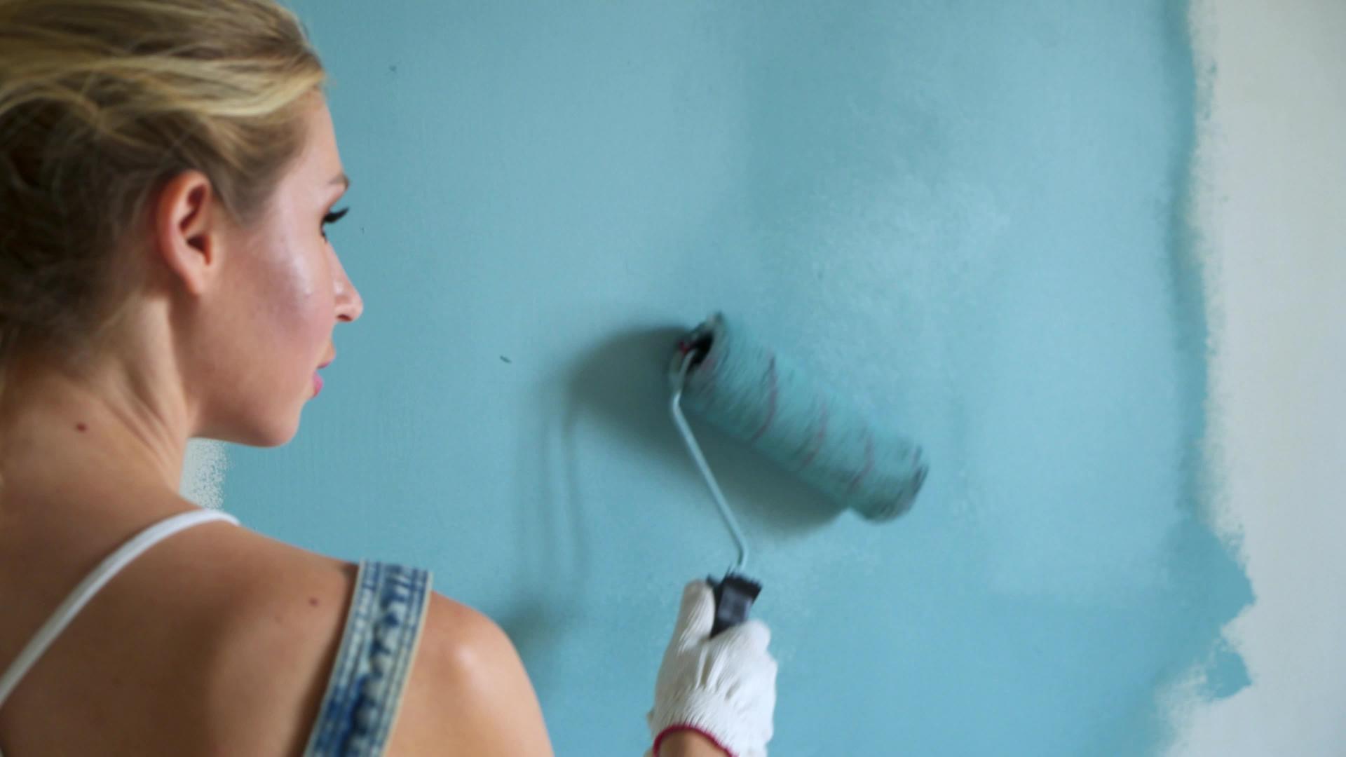 女工在公寓里用桶装滚筒粉刷墙壁或墙壁视频的预览图