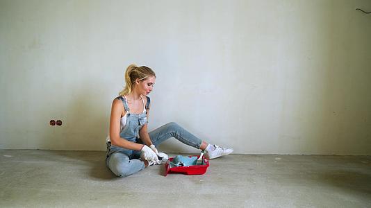 女工在公寓里用桶装滚筒粉刷墙壁或墙壁视频的预览图