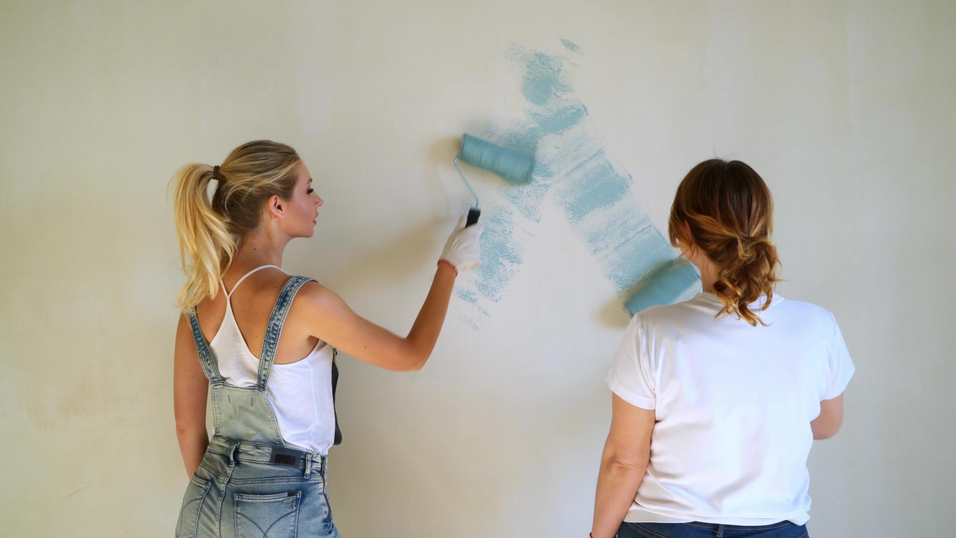 两名女工在公寓或房子里用滚动机油漆墙壁视频的预览图