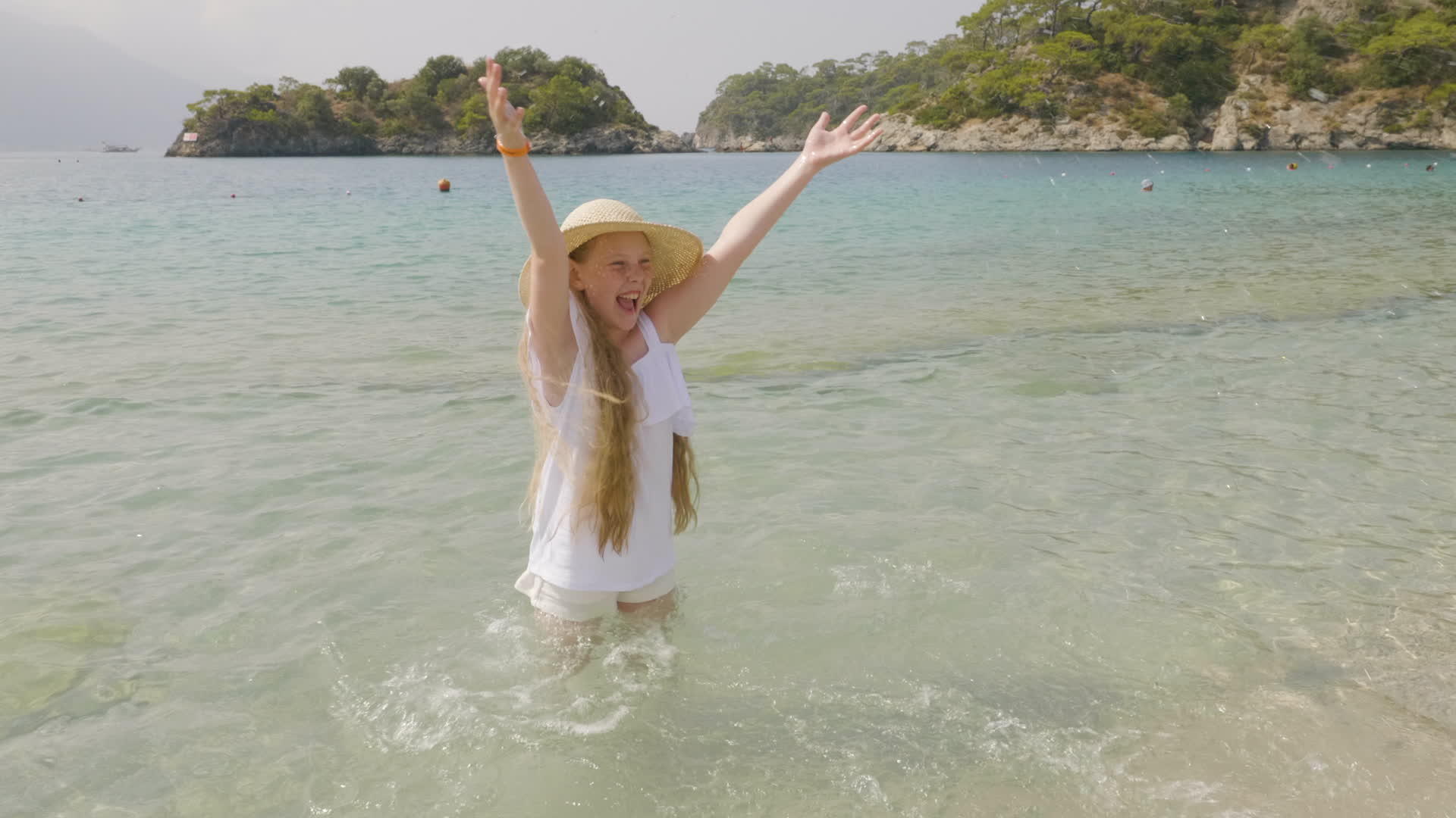 无忧无虑的女孩在天堂海滩上溅起海水戴着草帽视频的预览图