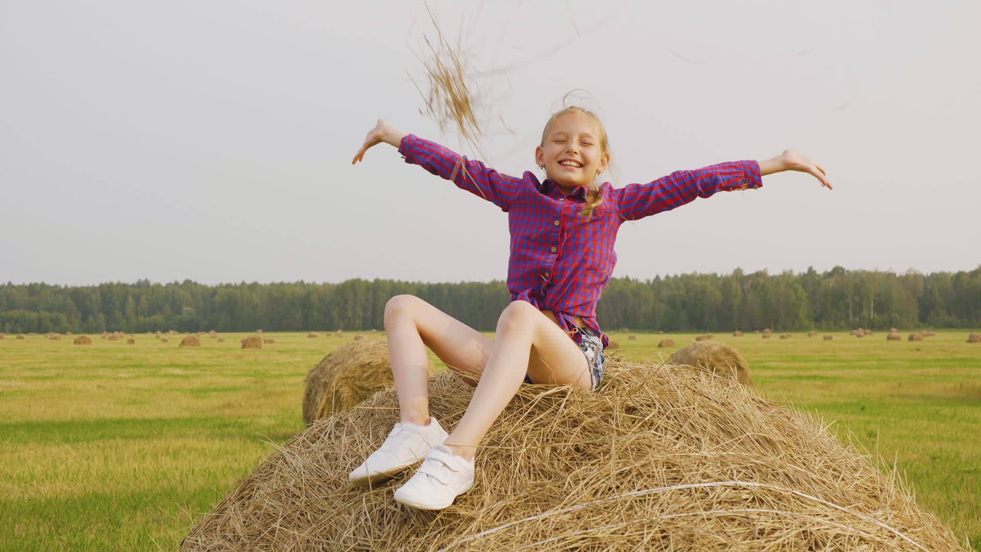 快乐的女孩坐在干草堆上年轻女孩在秋天的收割场玩得很开心视频的预览图