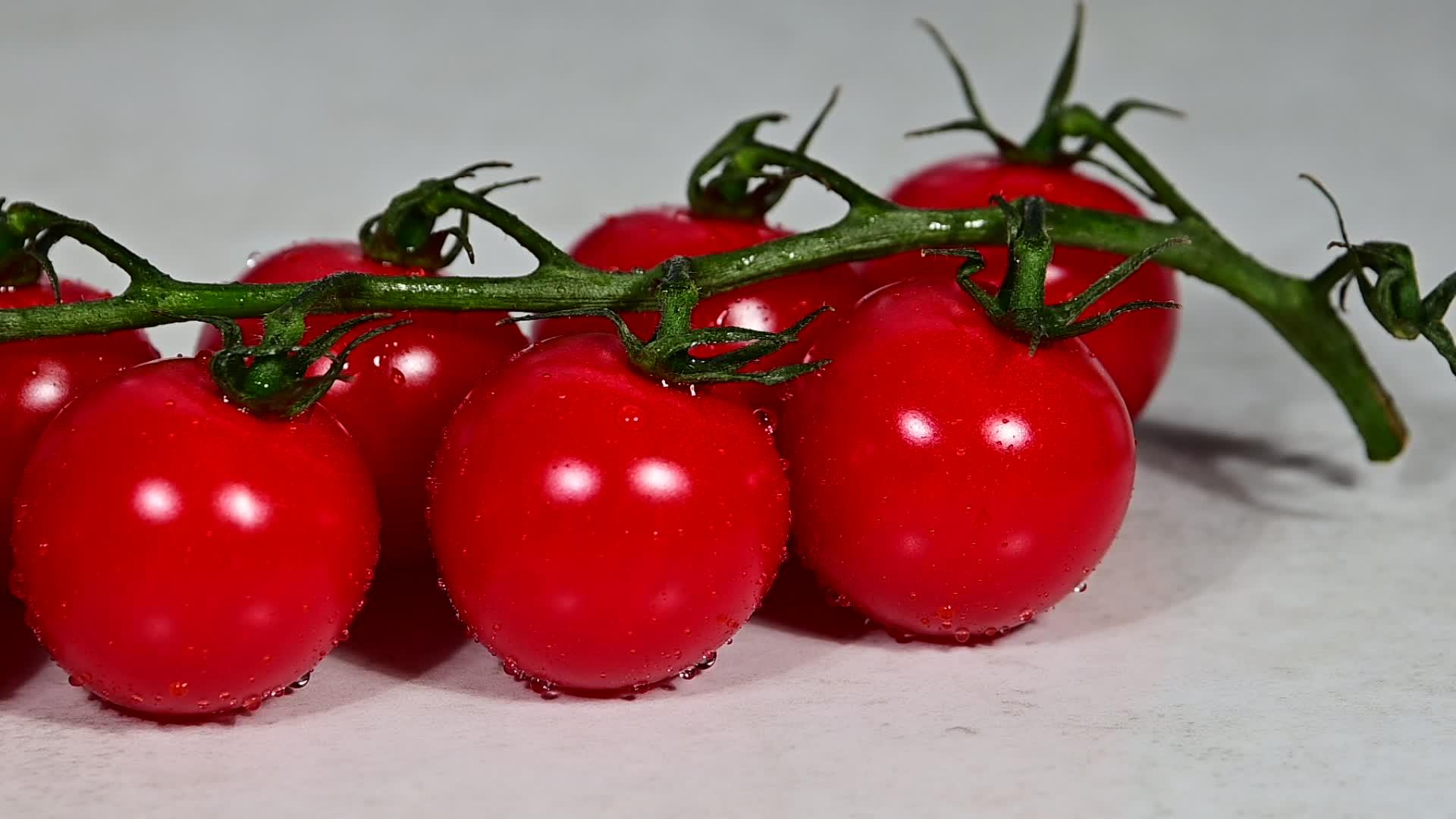 一堆红樱桃番茄倒在水滴上视频的预览图