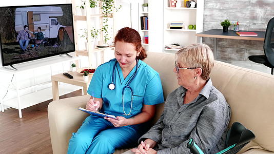 养老院的护理人员在与老年退休妇女交谈时在剪贴板上做笔记视频的预览图