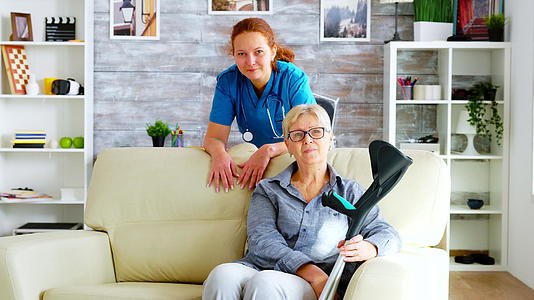 美丽的疗养院护士和坐在沙发上的老妇人视频的预览图