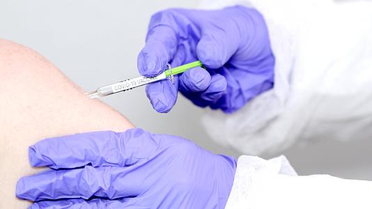 微生物学家或带有蓝色手术手套的医务工作者给予疫苗注射视频的预览图