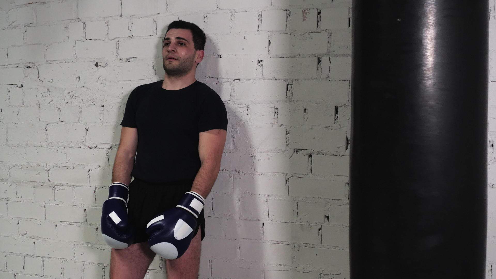 在健身房的砖墙上汗流浃背的拳击手靠在身上视频的预览图