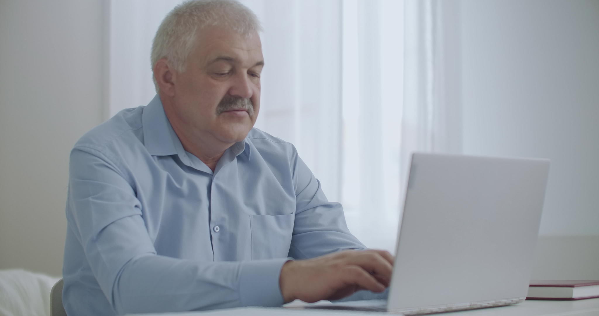 疲惫的男人在办公室用笔记本电脑工作伸手放松下葬视频的预览图