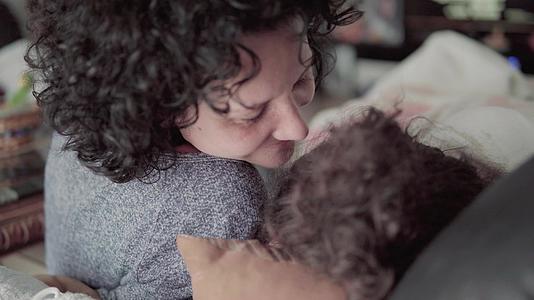 触摸生病的小女孩的母亲亲吻和拥抱躺在床上的生病女孩视频的预览图