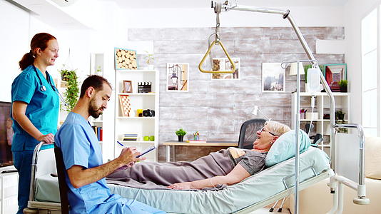 检查躺在医院床上的一名老妇人的男女护士队伍和视频的预览图
