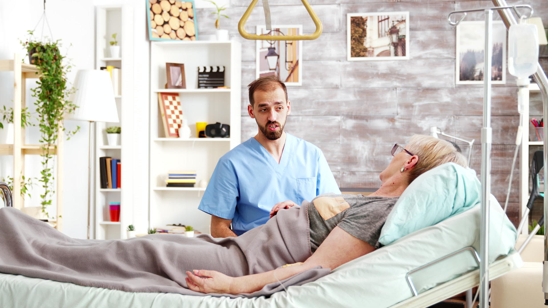 男医生和躺在疗养院病床上的老妇人交谈视频的预览图