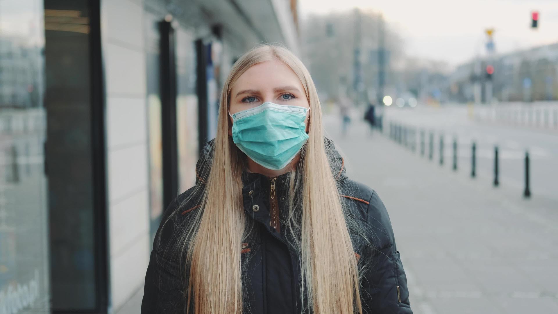 年轻的金发女郎在街上戴着保护性医疗面具视频的预览图