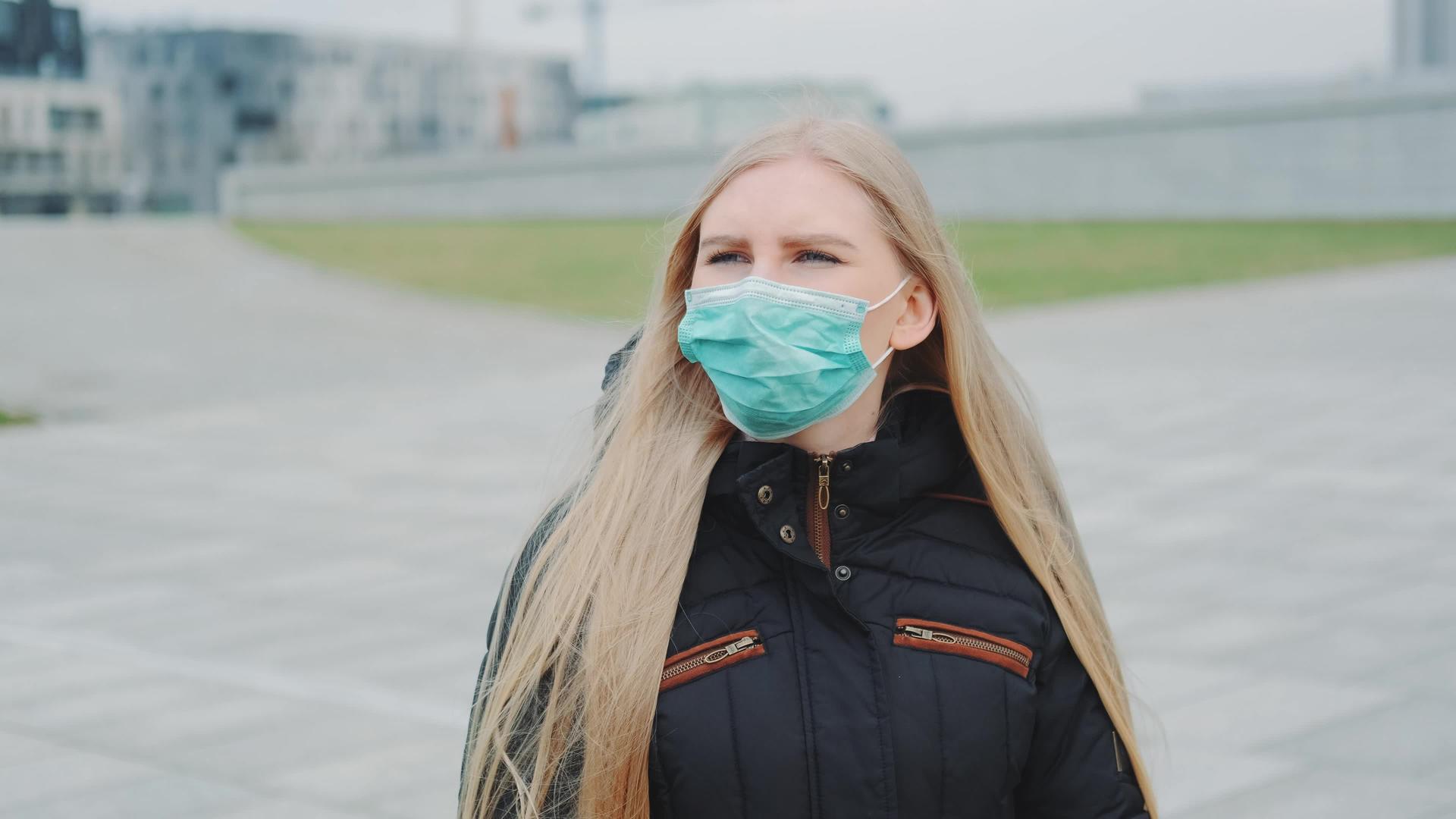 戴着保护性医疗面具的妇女在街上行走视频的预览图