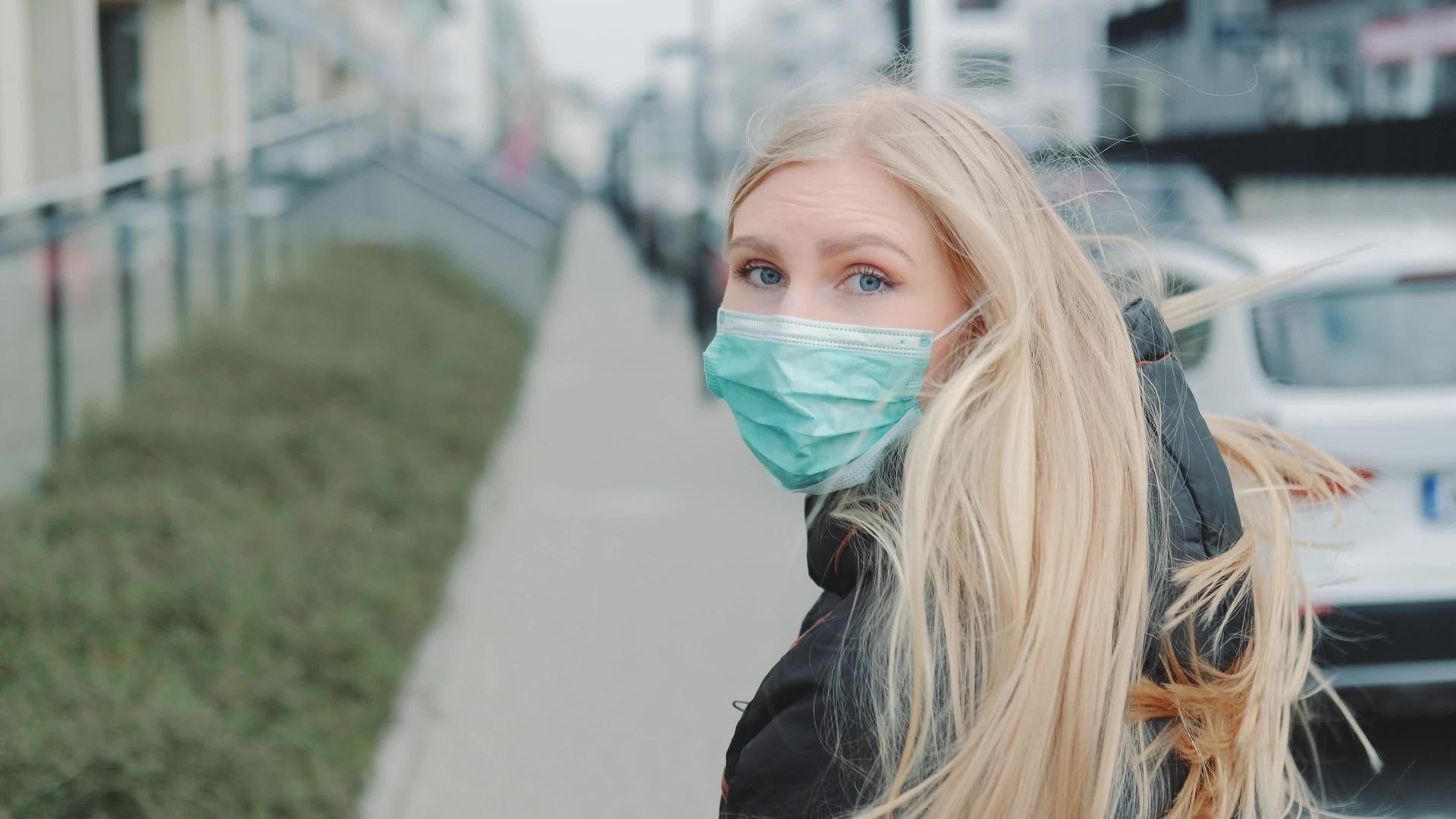 戴着医用面具的金发年轻女孩从街上的某个人手中逃脱视频的预览图
