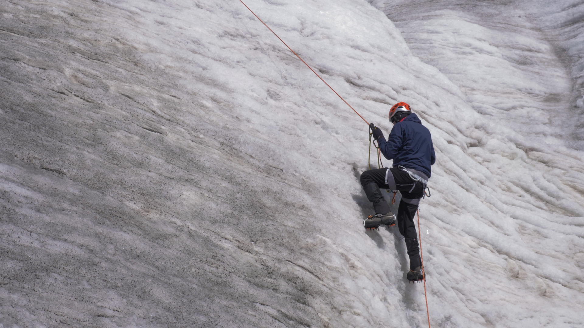 山人穿着固定绳索的裤子Jumar爬上山顶陡峭的雪坡视频的预览图