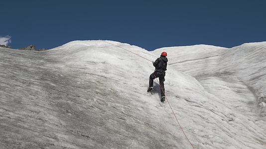 在阳光明媚的天气里山顶上穿着裤子和头盔的山人用固定绳子固定绳子视频的预览图
