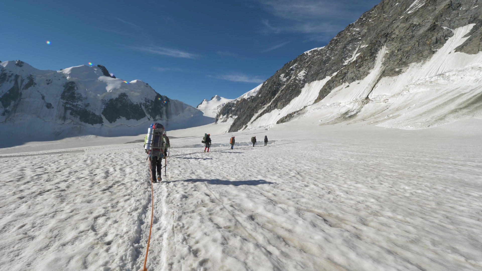一群背着背包的登山者被绑在一起在阳光明媚的日子里在雪山里视频的预览图