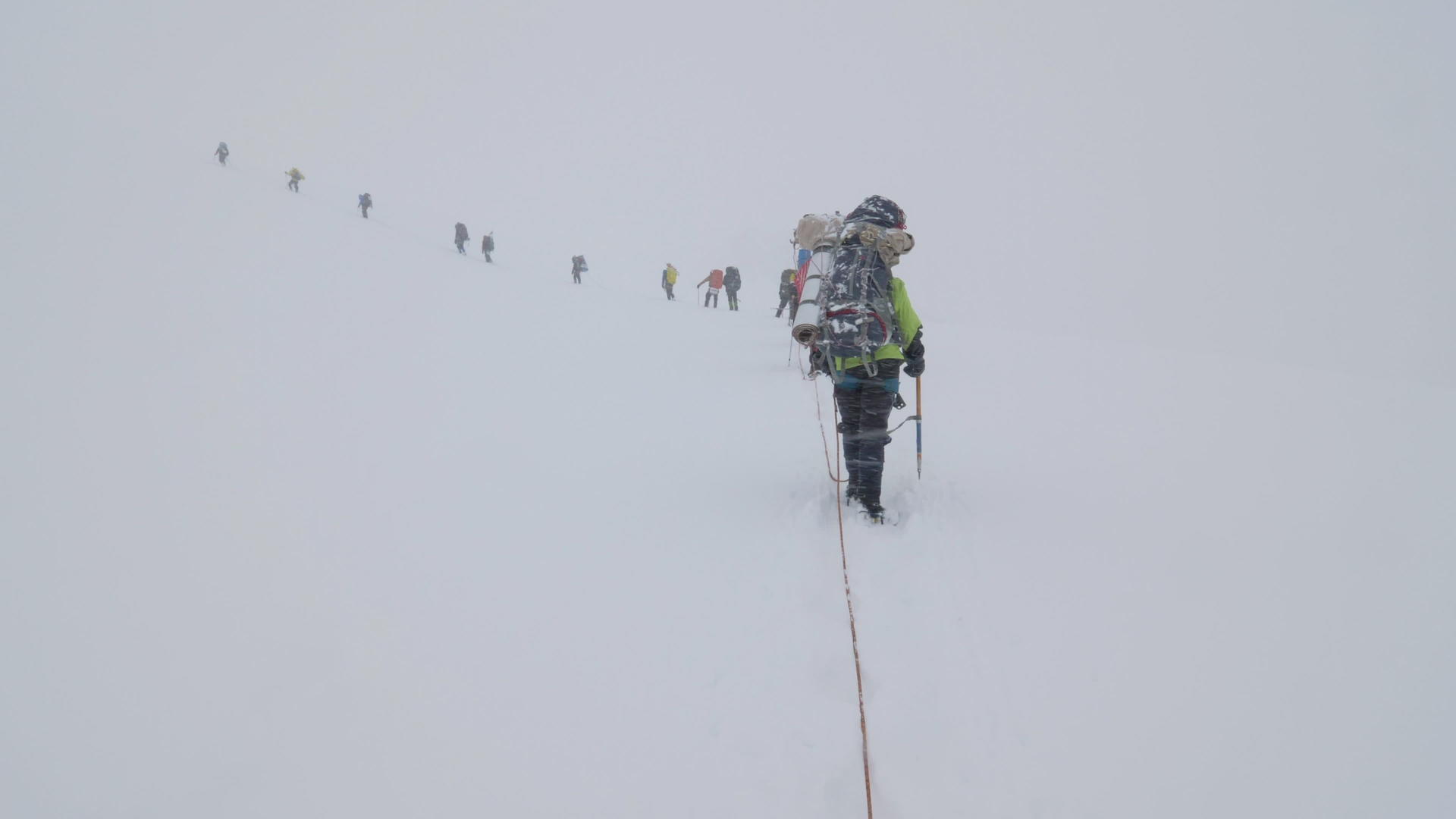 一群背着背包的登山者被绑在雪崩下雪山的冰川里视频的预览图