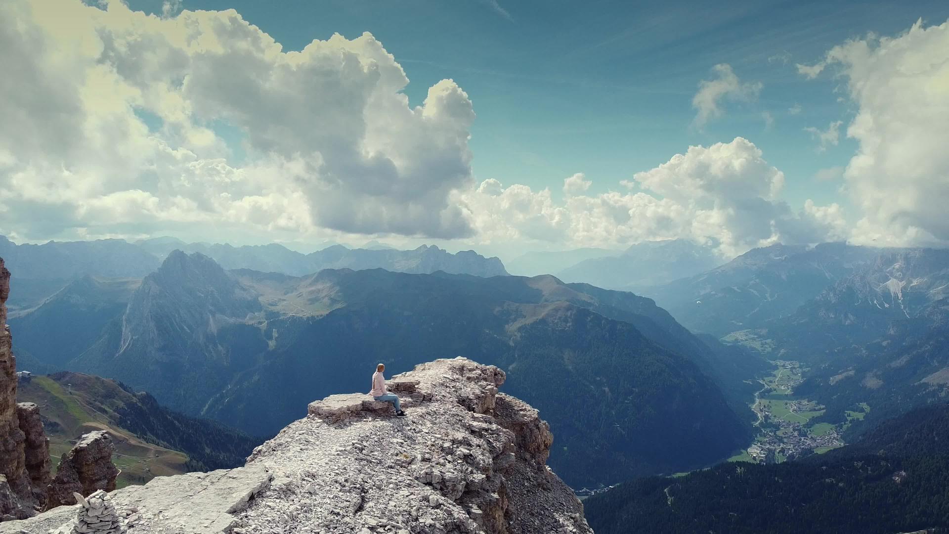 坐在多洛米特皮兹波伊山顶上的女人向后飞去视频的预览图