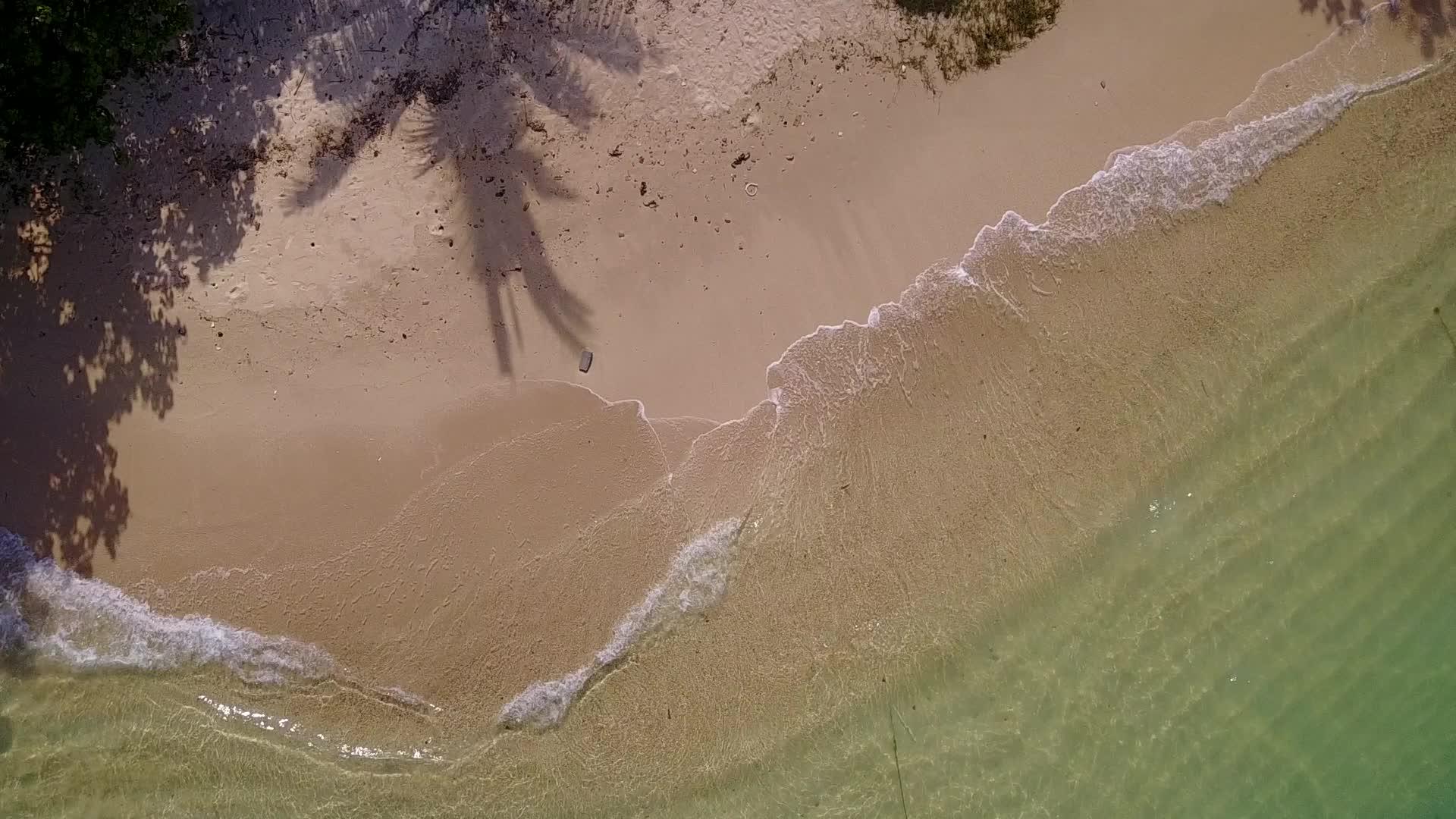 海上的绿色海洋和冲浪附近的白沙背景打破了沿海海滩的完美景色视频的预览图